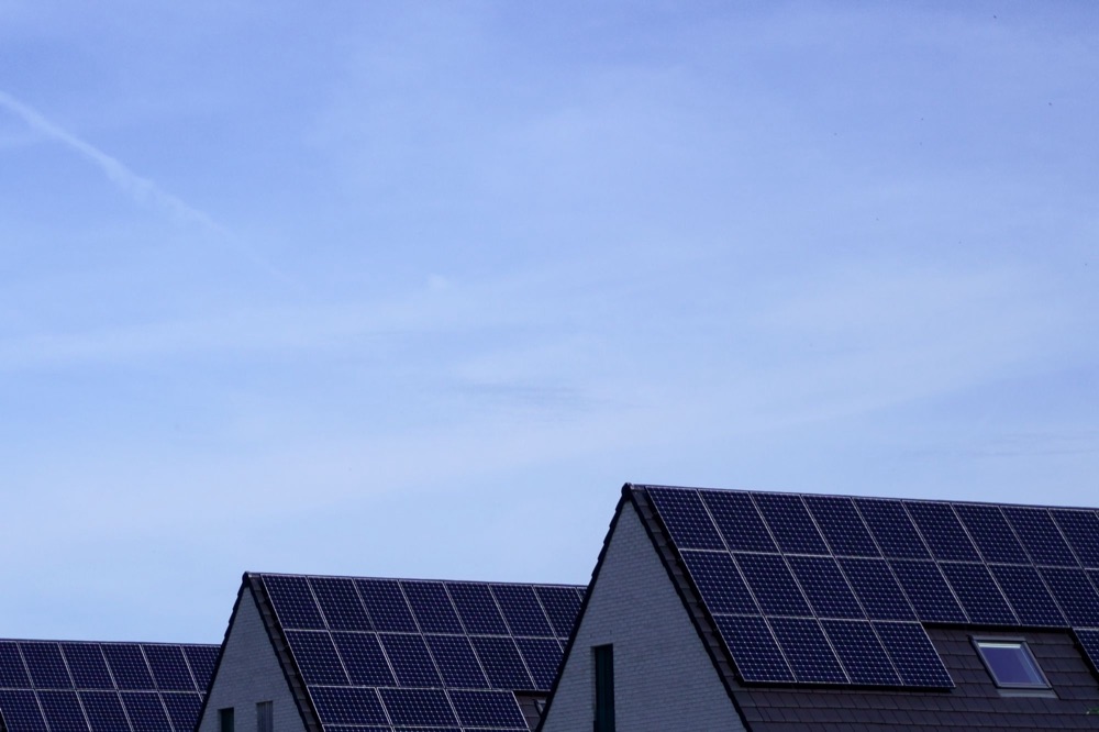 Rows of solar panels on dark roofs against a clear sky
