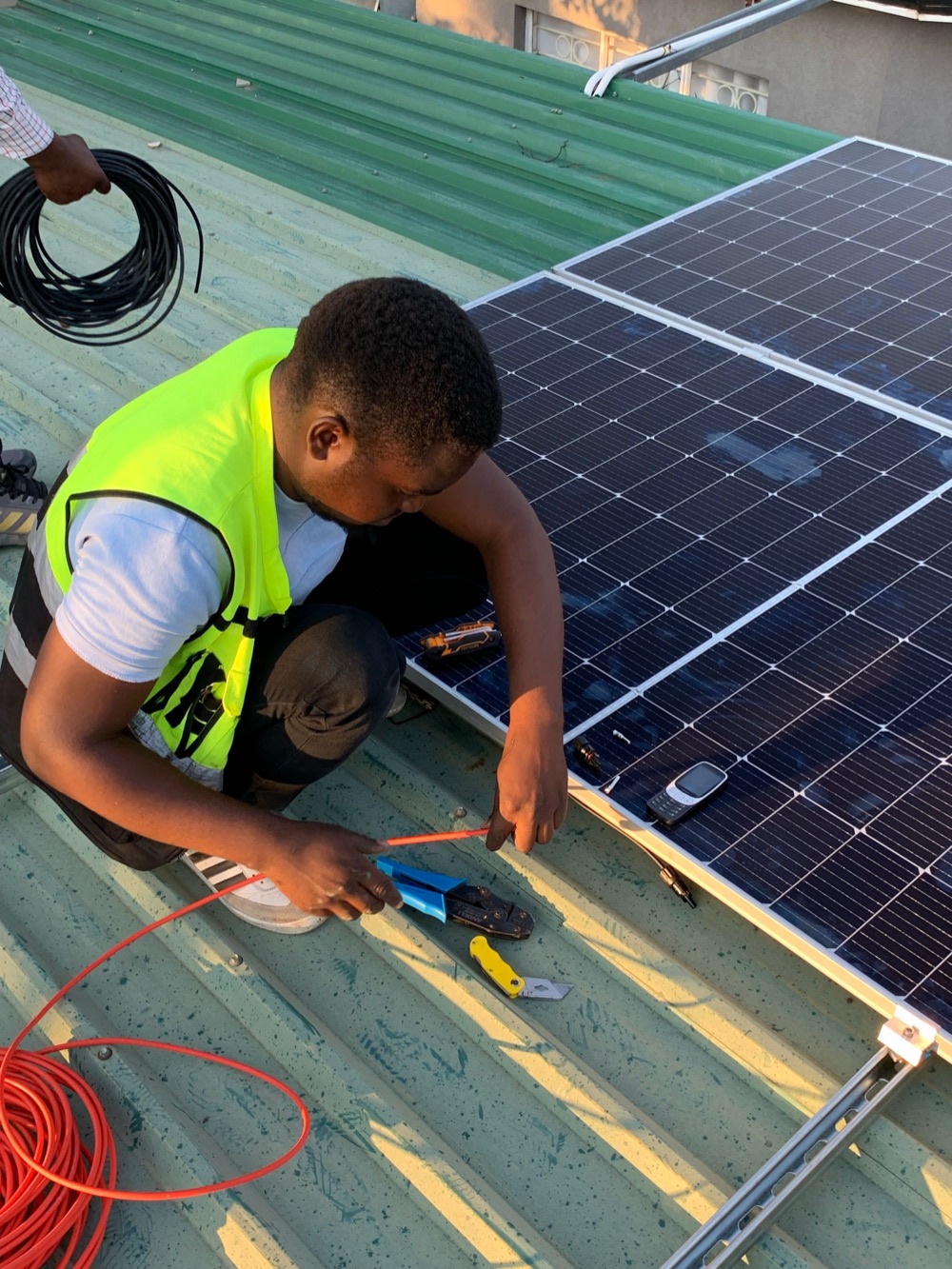 Installer in hi-vis fixing a panel on a roof