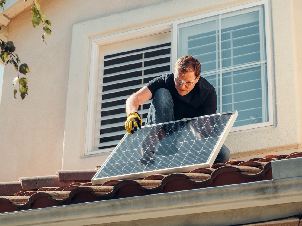 Installer fitting a solar panel on a tiled roof