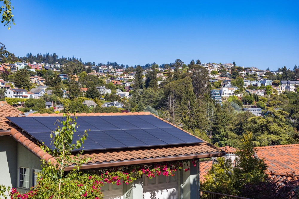Solar panels on a terracotta roof above a suburb